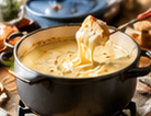 Fonduepan met gesmolten kaas en een stukje brood